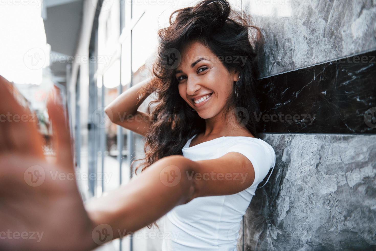 fille positive. belle femme aux cheveux noirs bouclés passer du bon temps dans la ville pendant la journée photo