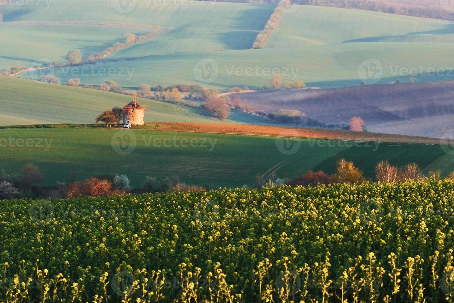 paysage majestueux de champ le soir. moulin à vent au centre du pré photo