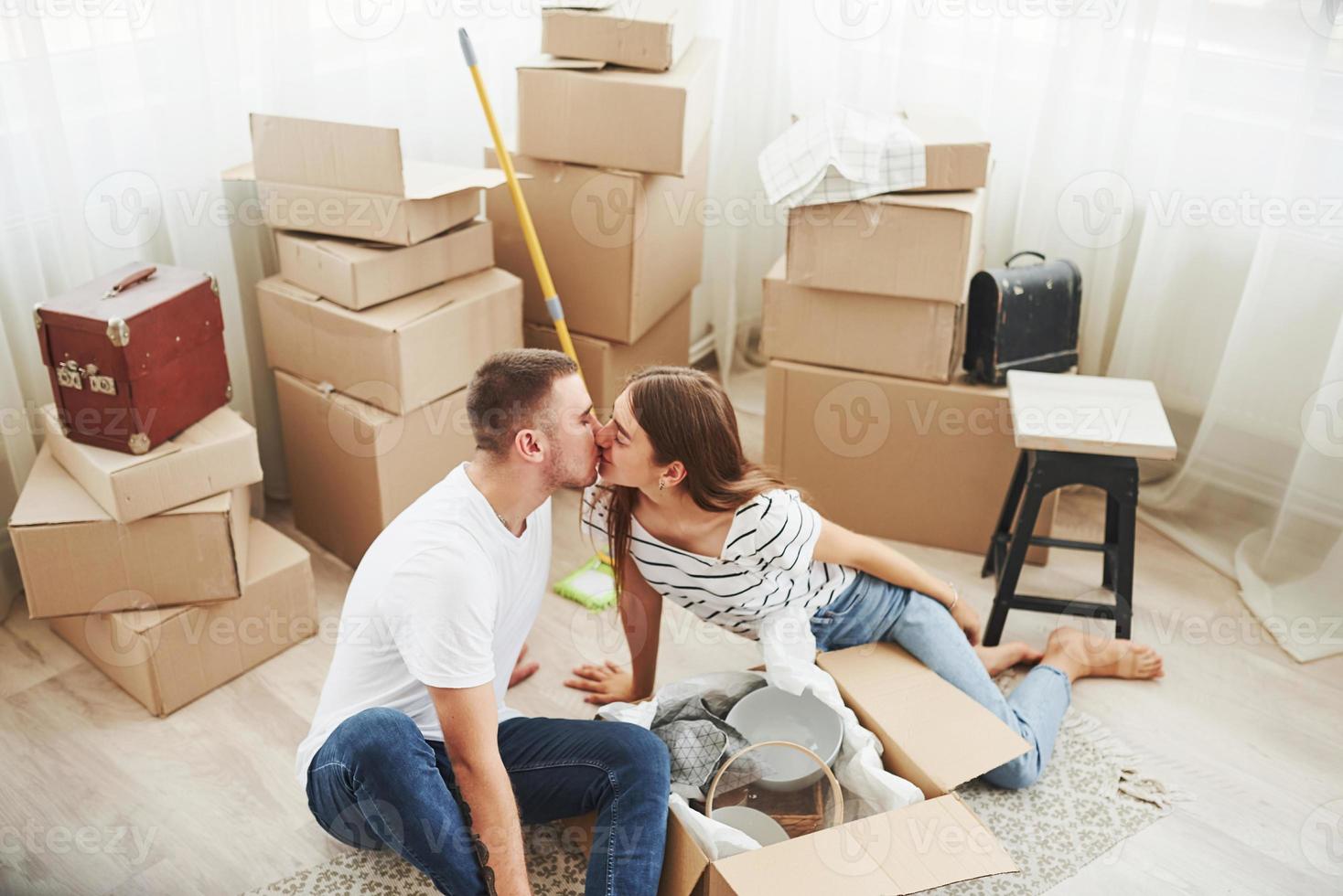 des gens adorables qui s'embrassent. joyeux jeune couple dans leur nouvel appartement. conception du déménagement photo