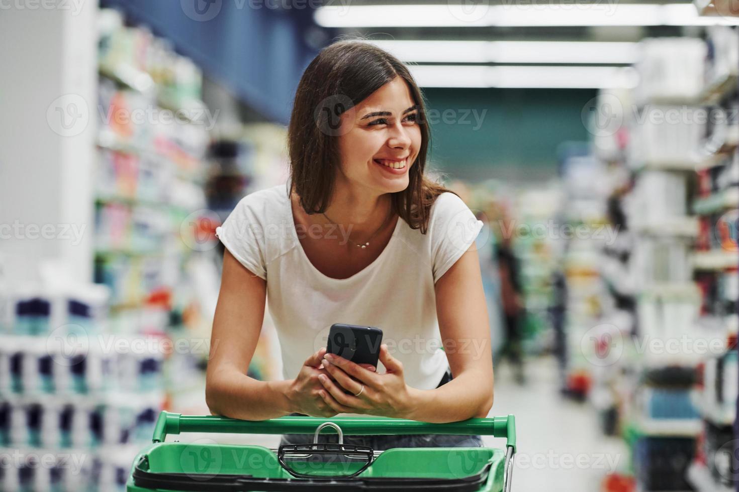 à l'aide d'un téléphone intelligent. femme cliente en vêtements décontractés sur le marché à la recherche de produits photo