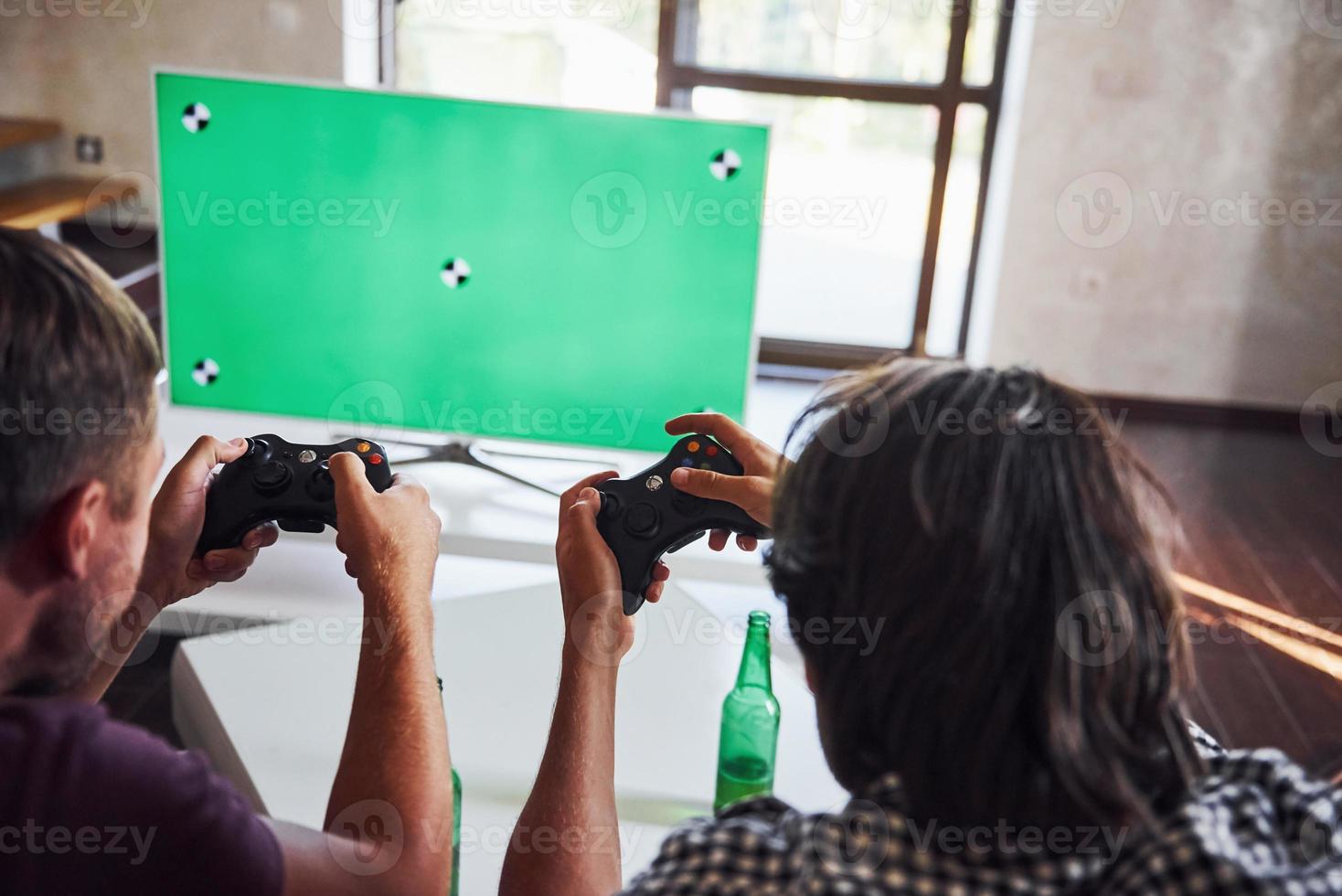 bière sur la table. un groupe d'amis s'amuse à jouer à un jeu de console à l'intérieur dans le salon photo