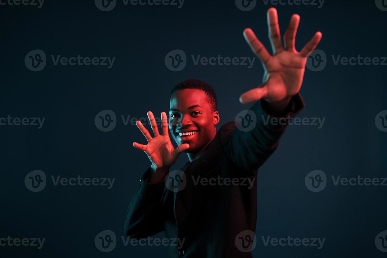 s'amuser. éclairage néon futuriste. jeune homme afro-américain dans le studio photo