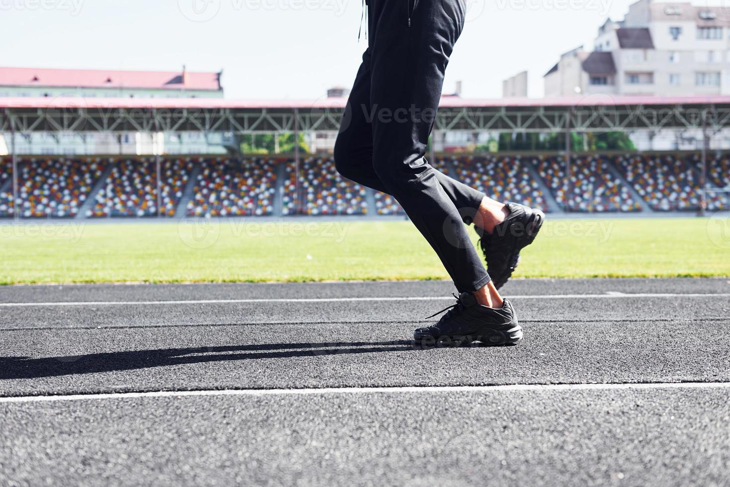 vue rapprochée des jambes du coureur en pantalon noir et chaussures qui est à l'extérieur sur la piste photo