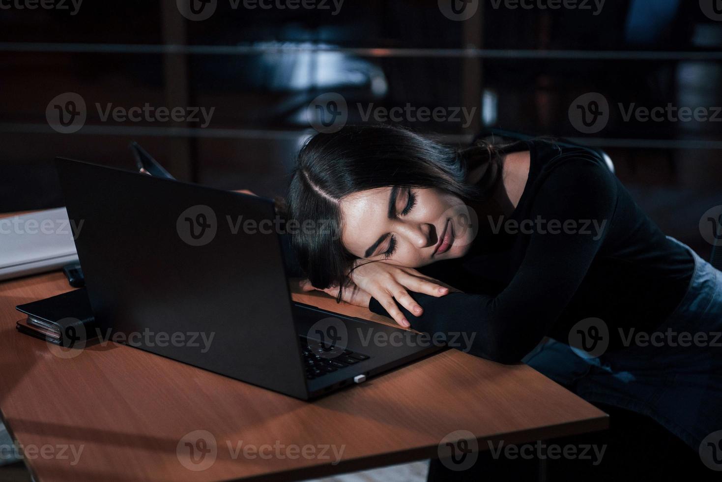 va juste fermer les yeux pendant quelques minutes. jolie femme d'affaires brune travaille seule au bureau la nuit photo