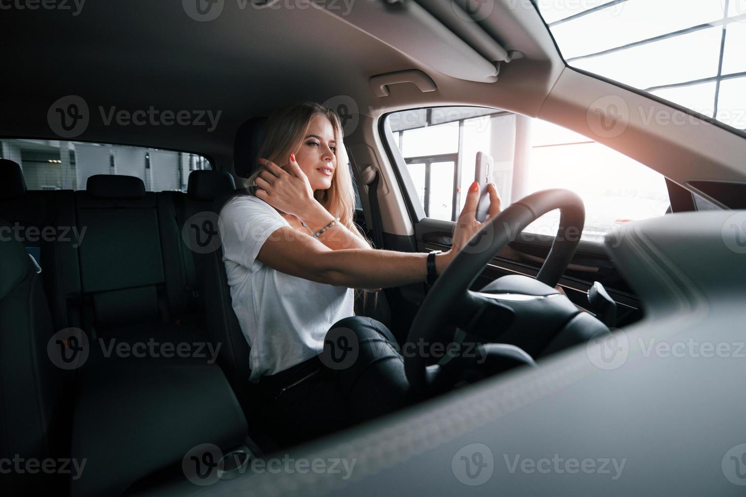 belle et charmante. fille en voiture moderne dans le salon. la journée à l'intérieur. achat d'un véhicule neuf photo