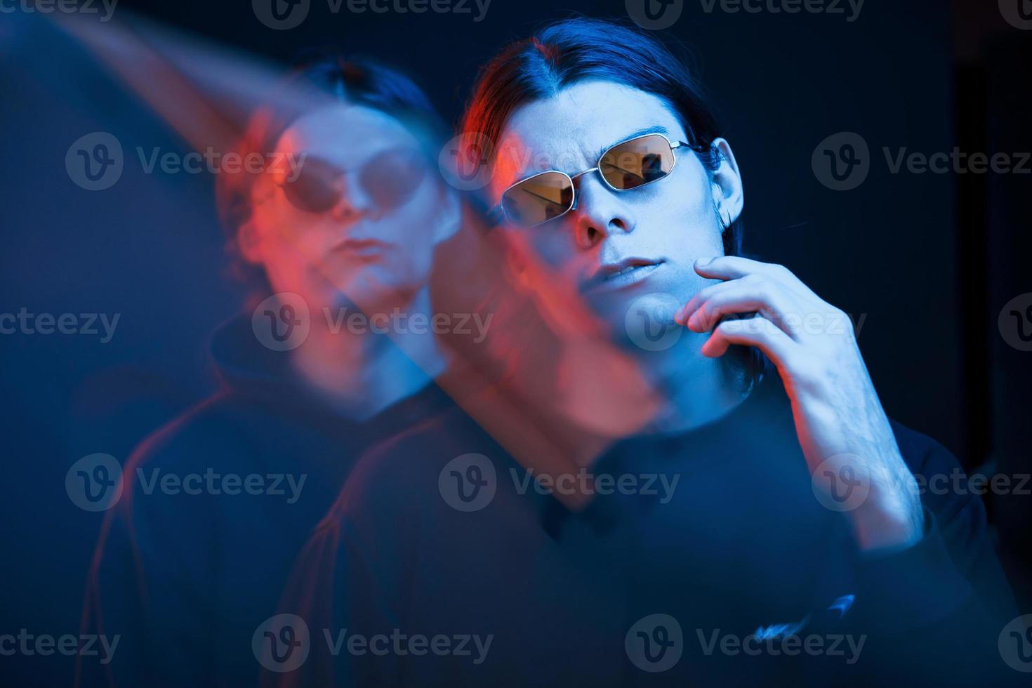 en lunettes de soleil dans la chambre. portrait de frères jumeaux. tourné en studio dans un studio sombre avec néon photo