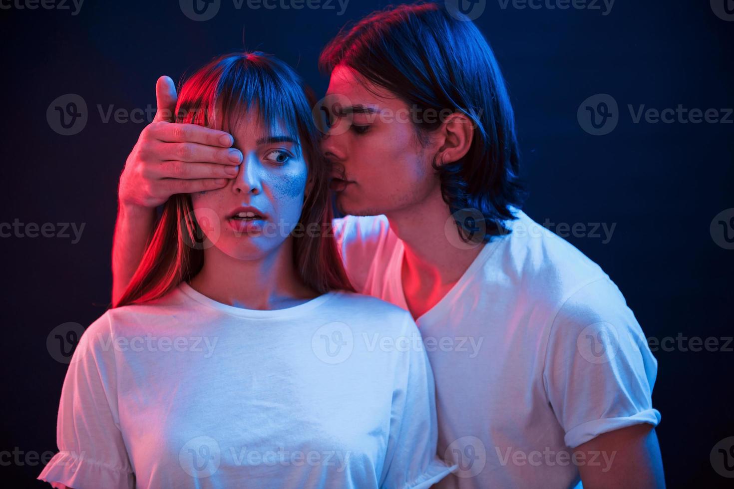 cela va vous choquer. couple debout dans une pièce sombre avec éclairage au néon rouge et bleu photo