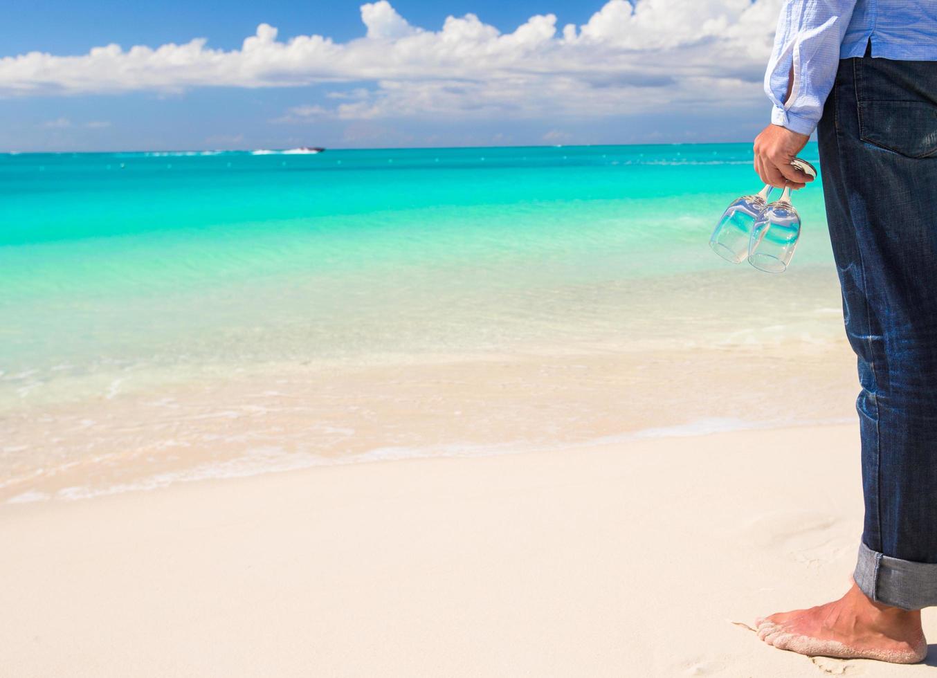 homme tenant des verres à vin sur une plage tropicale photo