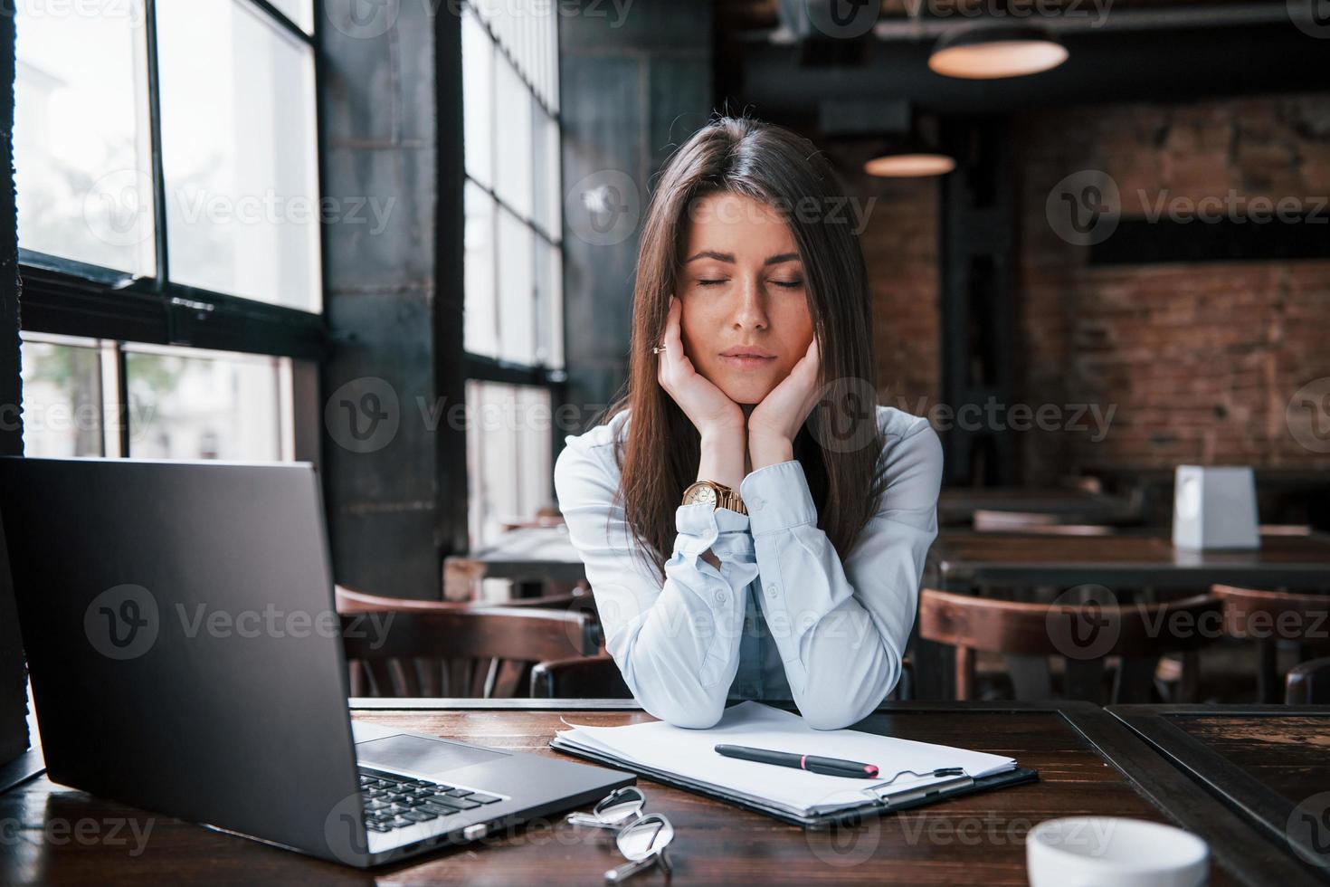 fatigué après tout ce travail acharné. femme d'affaires en vêtements officiels est à l'intérieur dans un café pendant la journée photo