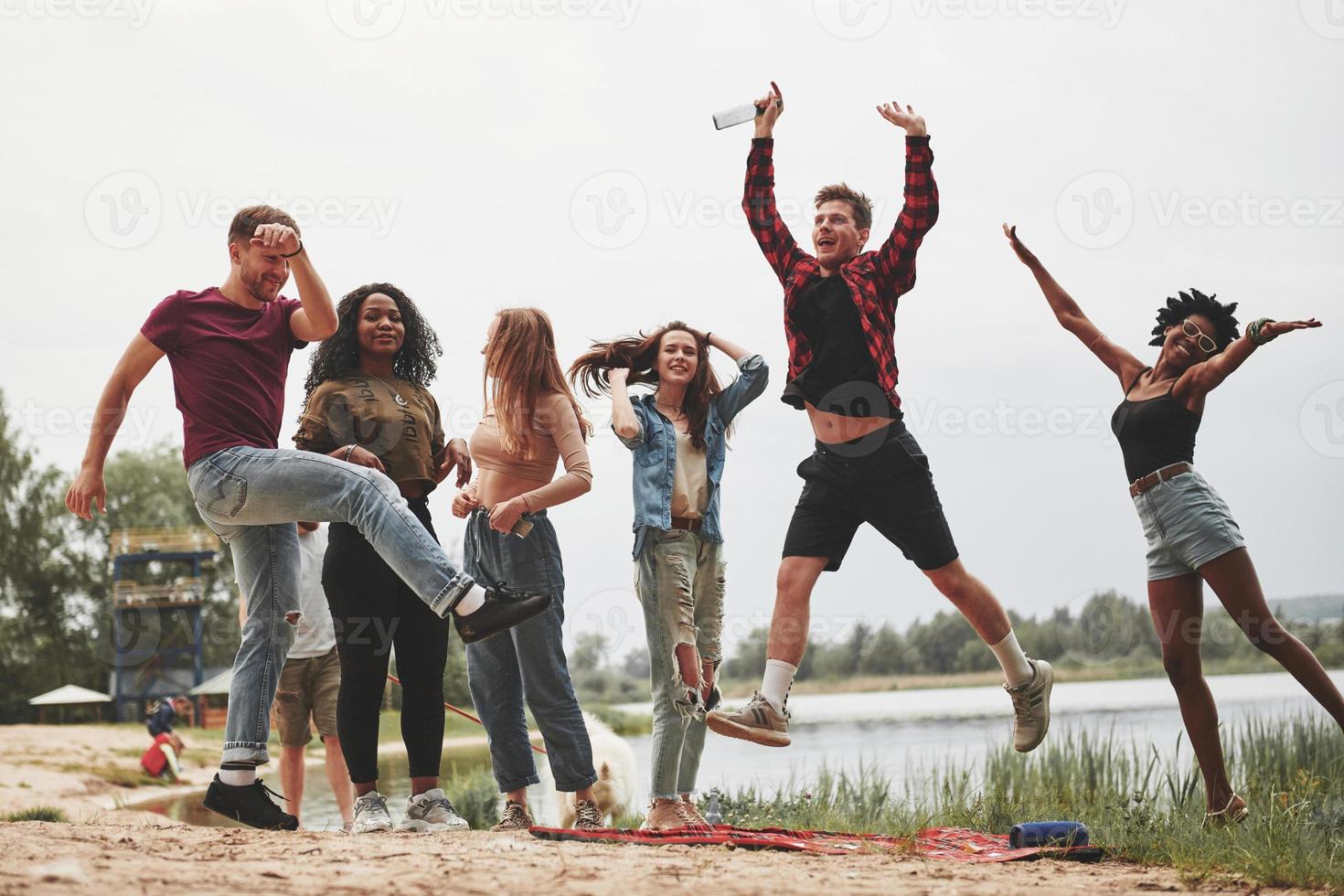 Faisons les fous. groupe de personnes pique-nique sur la plage. les amis s'amusent le week-end photo