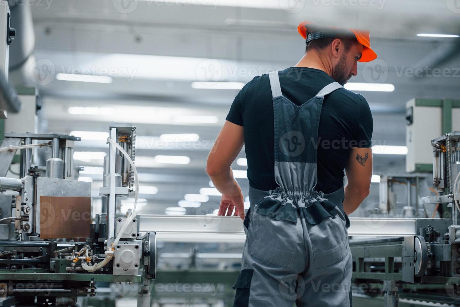 prenant la fenêtre. ouvrier industriel à l'intérieur de l'usine. jeune technicien avec casque orange photo