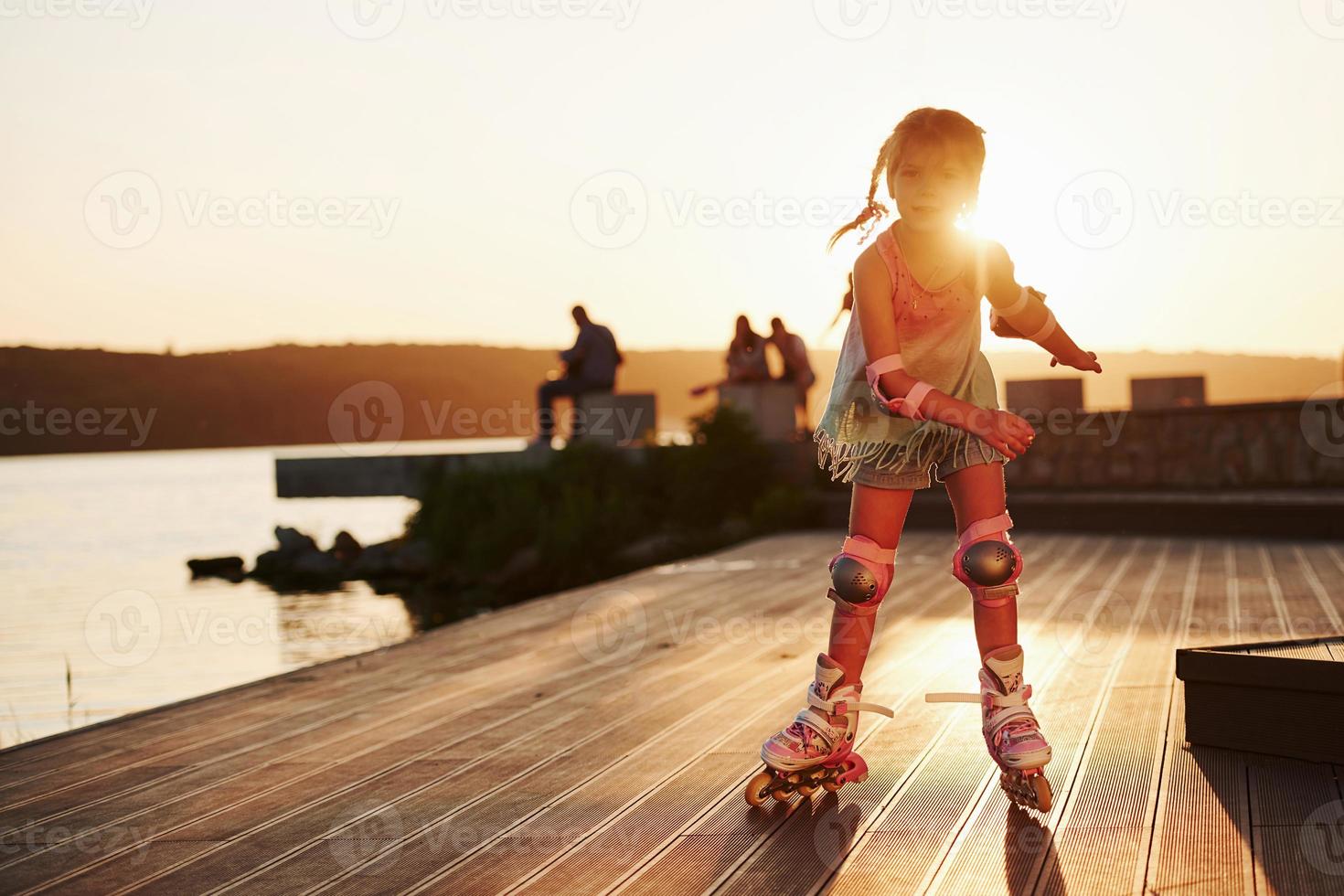 joyeux enfant mignon à cheval sur ses patins à roulettes. lumière du soleil incroyable photo