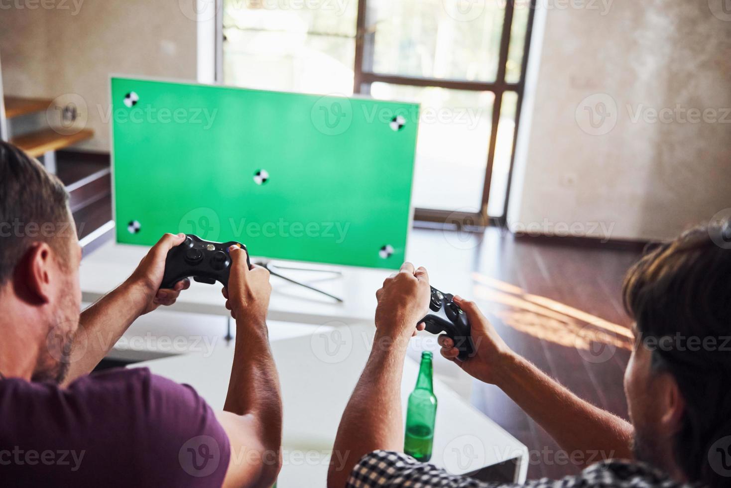 bière sur la table. un groupe d'amis s'amuse à jouer à un jeu de console à l'intérieur dans le salon photo