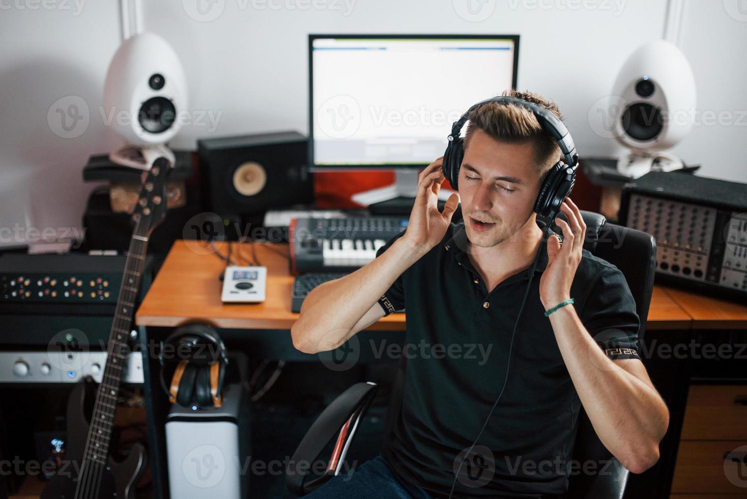 satisfait de la qualité audio. ingénieur du son dans les écouteurs travaillant et mélangeant de la musique à l'intérieur du studio photo