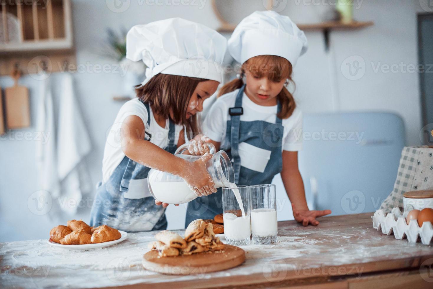 les biscuits sont prêts. enfants de la famille en uniforme de chef blanc préparant la nourriture dans la cuisine photo