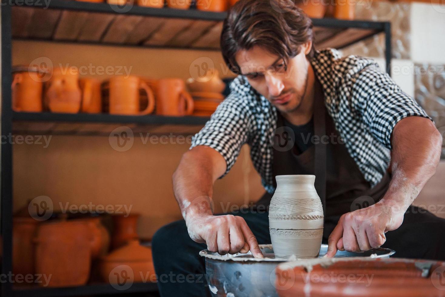 détailler avec un outil spécial. un céramiste utilise un tour de potier et crée un produit en argile fait à la main photo