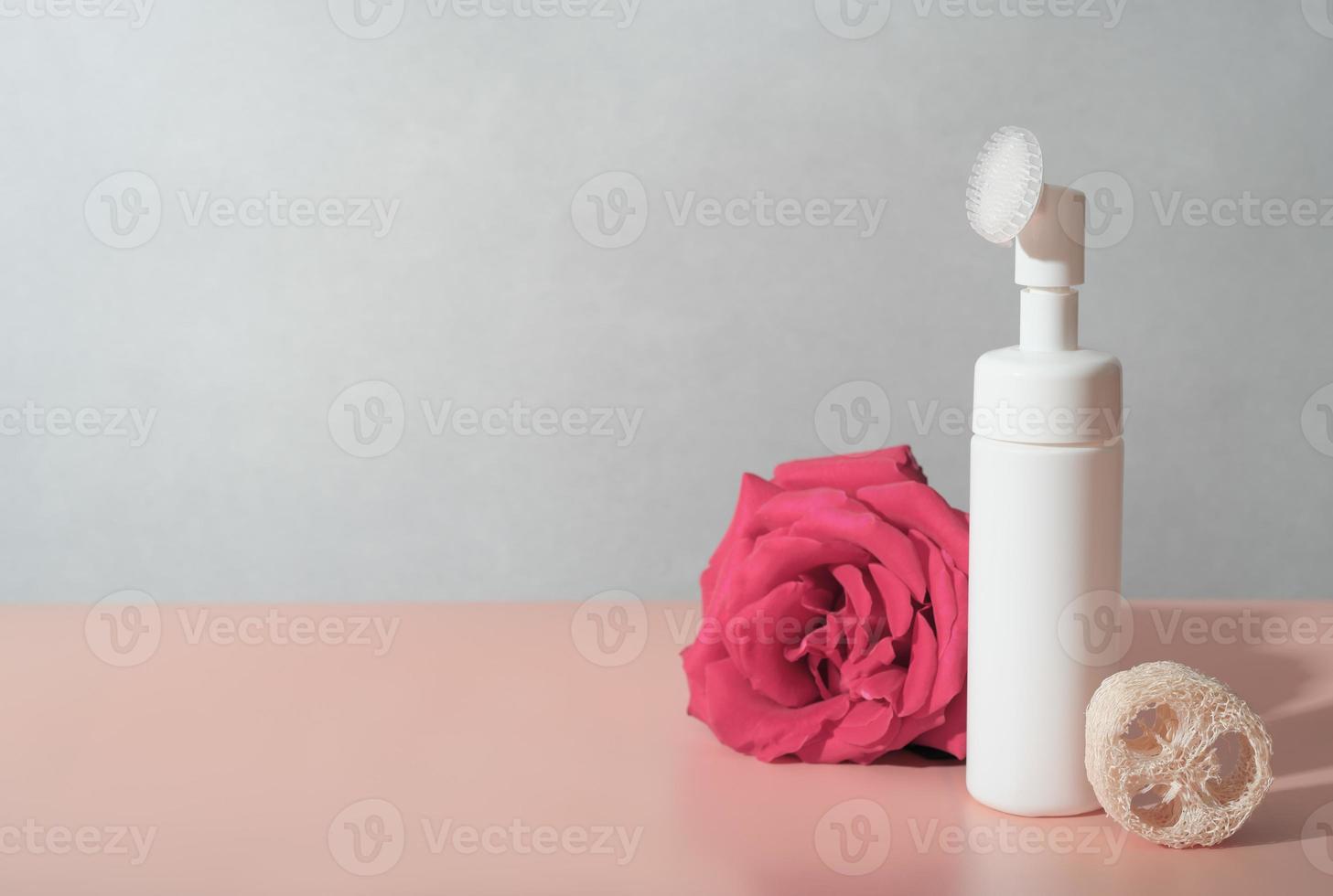 mousse nettoyante pour le visage dans une bouteille avec brosse intégrée. éponge de luffa naturelle. nettoyage de la peau du visage, massage et routine quotidienne. espace de copie. photo