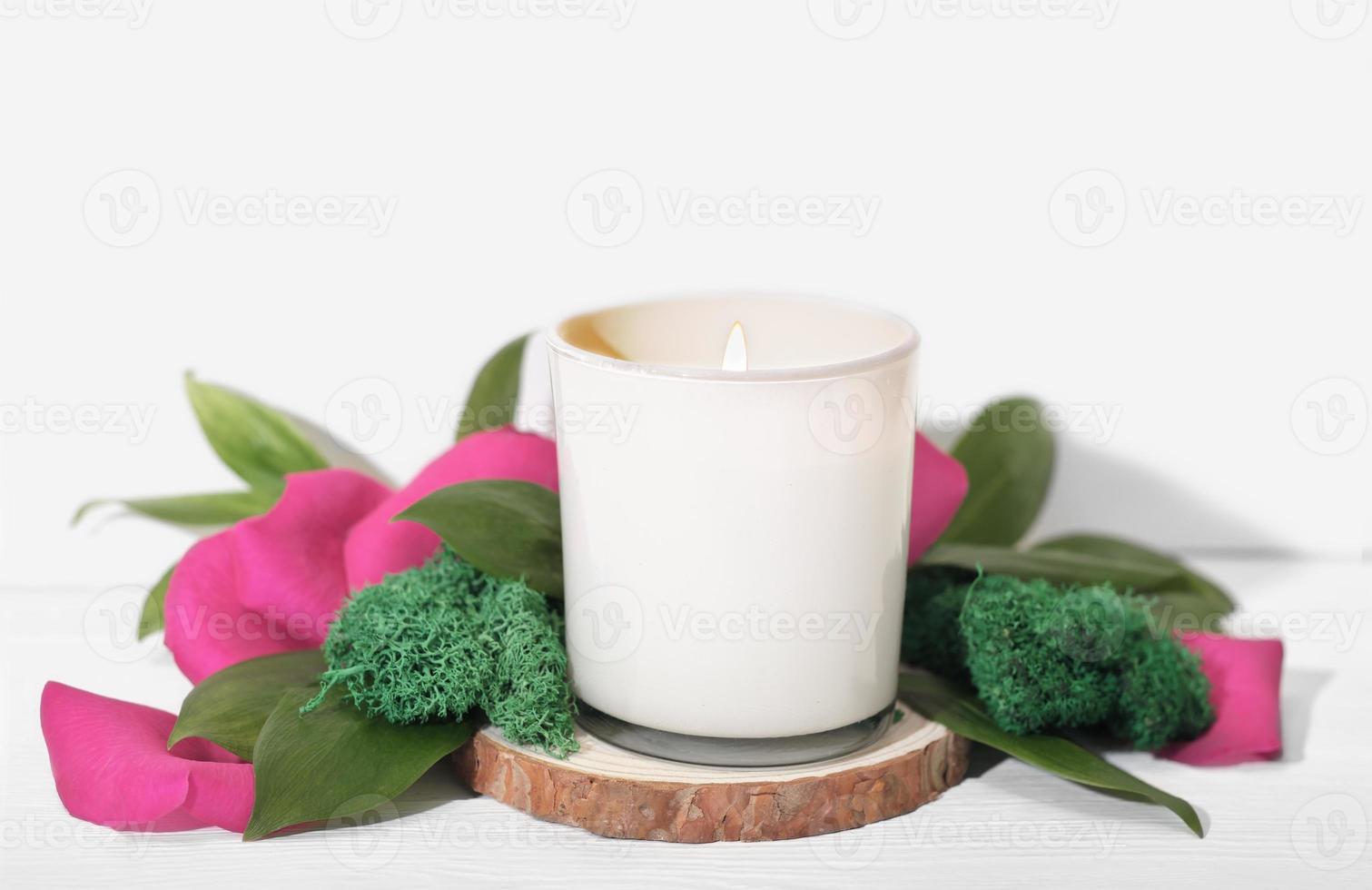 Bougie parfumée brûlante en verre blanc à décor de pétales de roses et de feuilles vertes. décoration de maison élégante, détails d'une maison confortable photo