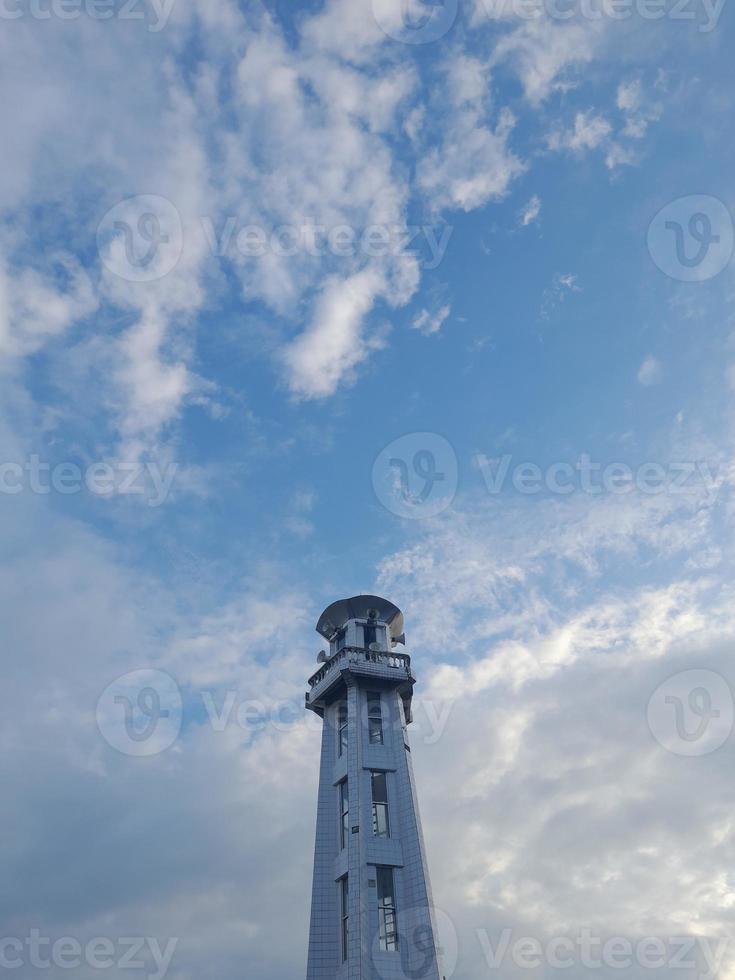 le minaret blanc de la mosquée de l'île de lombok, en indonésie, sur fond de ciel bleu avec des nuages blancs. photo