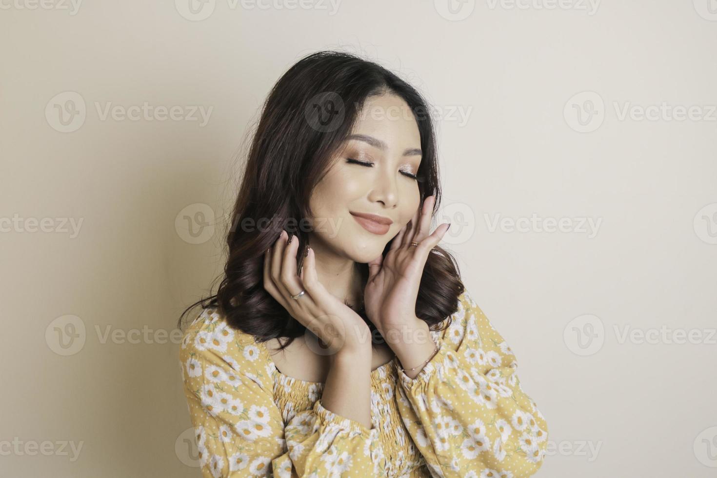 un visage gai de beauté d'un jeune mannequin asiatique portant un haut à fleurs jaune. soin du visage beauté soins de la peau, spa, concept de santé féminine. photo