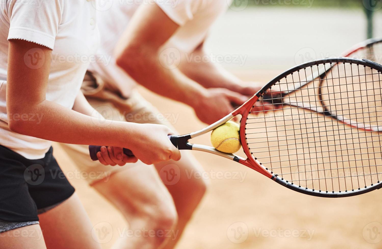 vue de côté. Entraîneur enseignant le jeu de tennis aux étudiantes dans la cour à l'extérieur photo