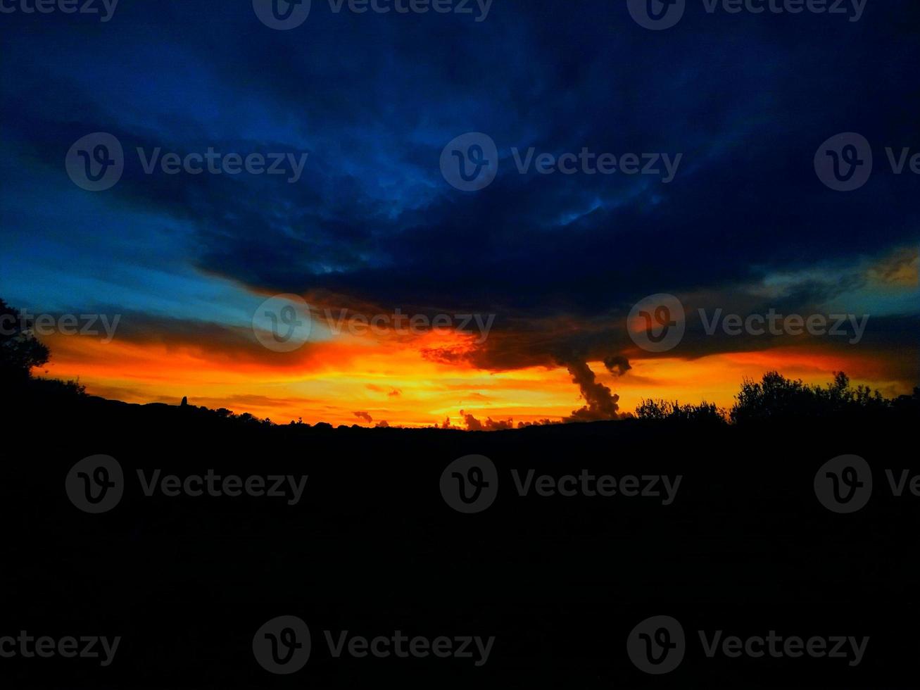 coucher de soleil rouge-orange avec des nuages aux tons bleus photo