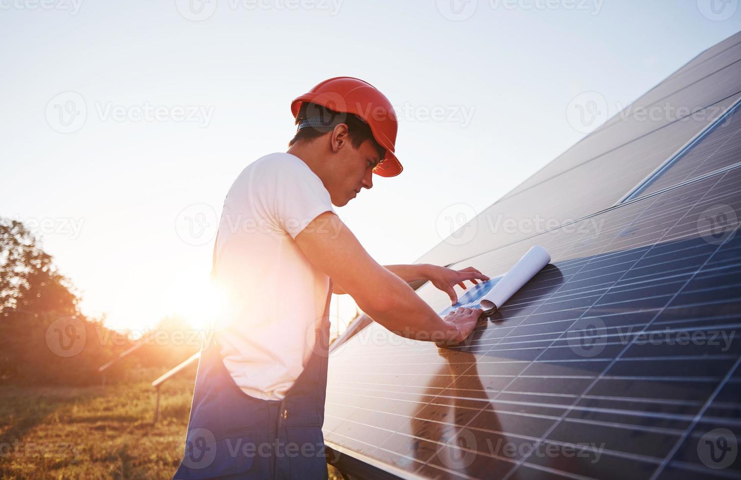 beau soleil. travailleur masculin en uniforme bleu à l'extérieur avec des batteries solaires photo