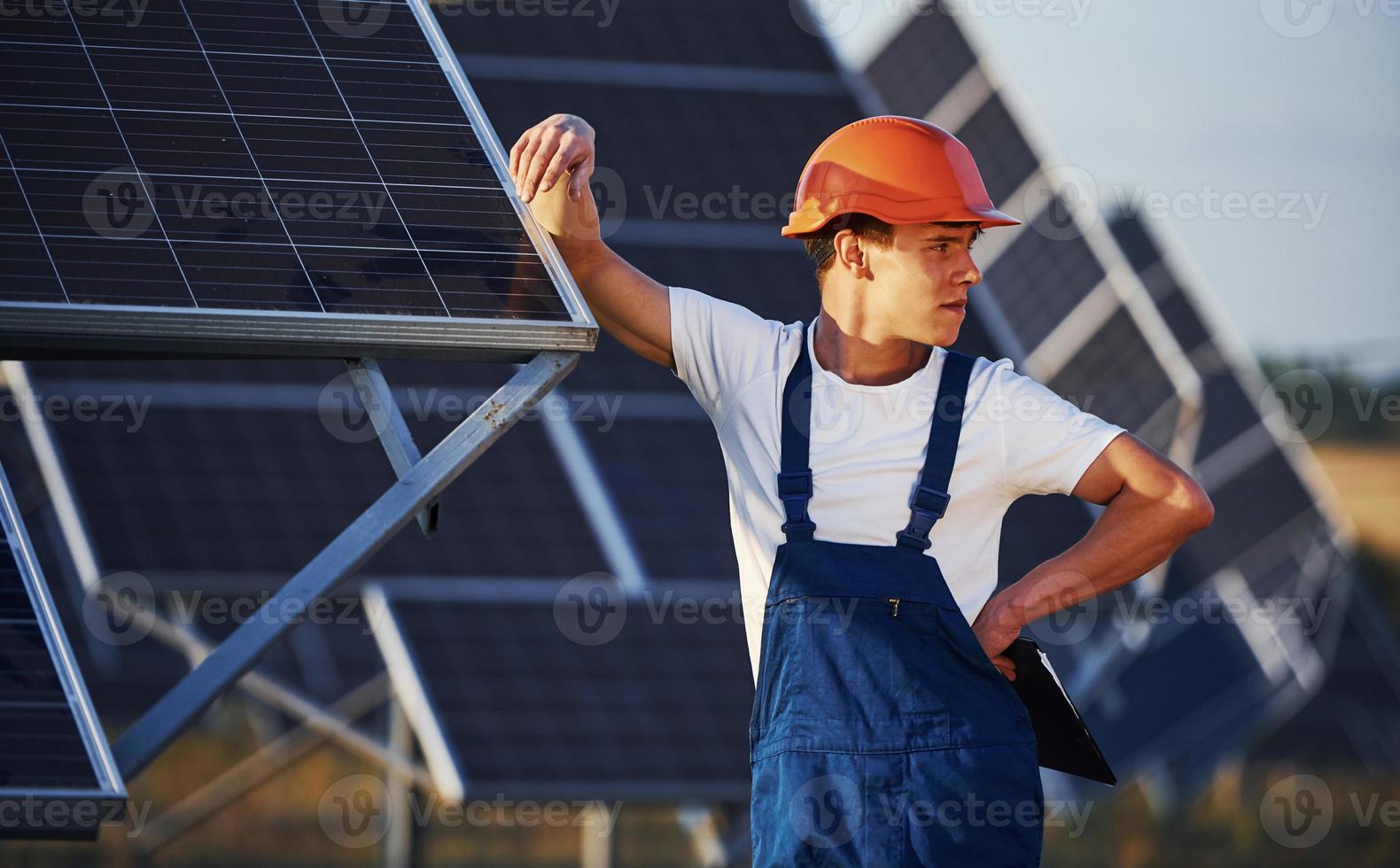 travailleur masculin en uniforme bleu à l'extérieur avec des batteries solaires à la journée ensoleillée photo