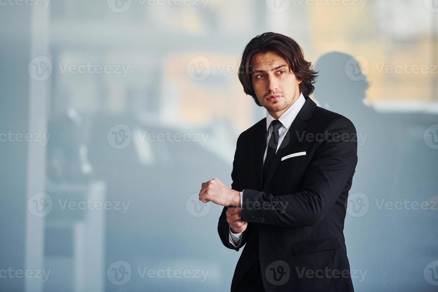 portrait de beau jeune homme d'affaires en costume noir et cravate photo