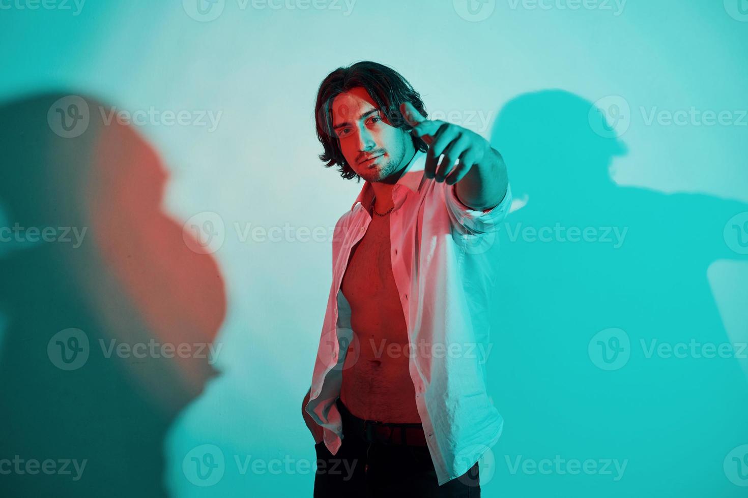 portrait de jeune homme chaud qui se tient dans des néons dans le studio photo