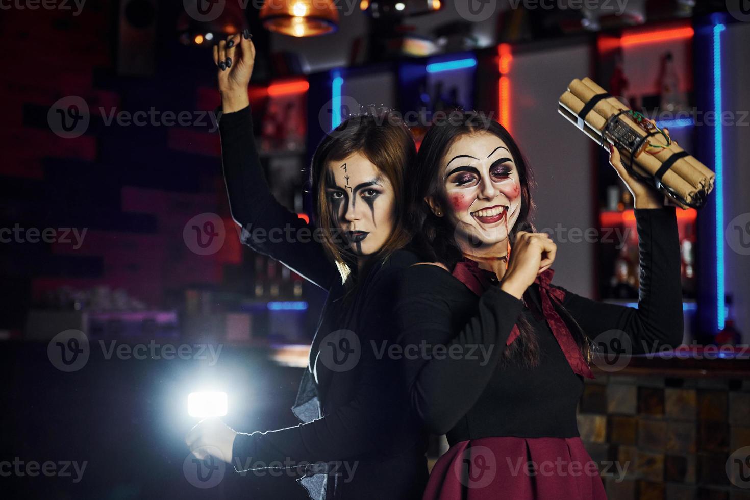 deux amies sont à la fête thématique d'halloween dans un maquillage effrayant et des costumes avec une bombe à retardement photo