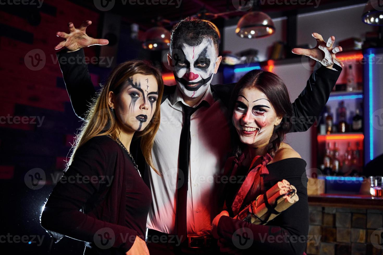 des amis sont à la fête d'halloween thématique dans un maquillage effrayant et des costumes s'amusent et posent ensemble pour la caméra photo