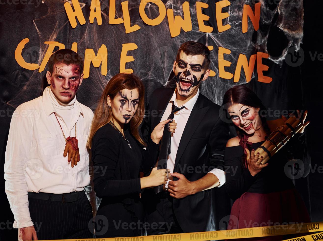 debout contre le mur de la scène du crime. les amis sont à la fête d'halloween thématique avec un maquillage et des costumes effrayants photo