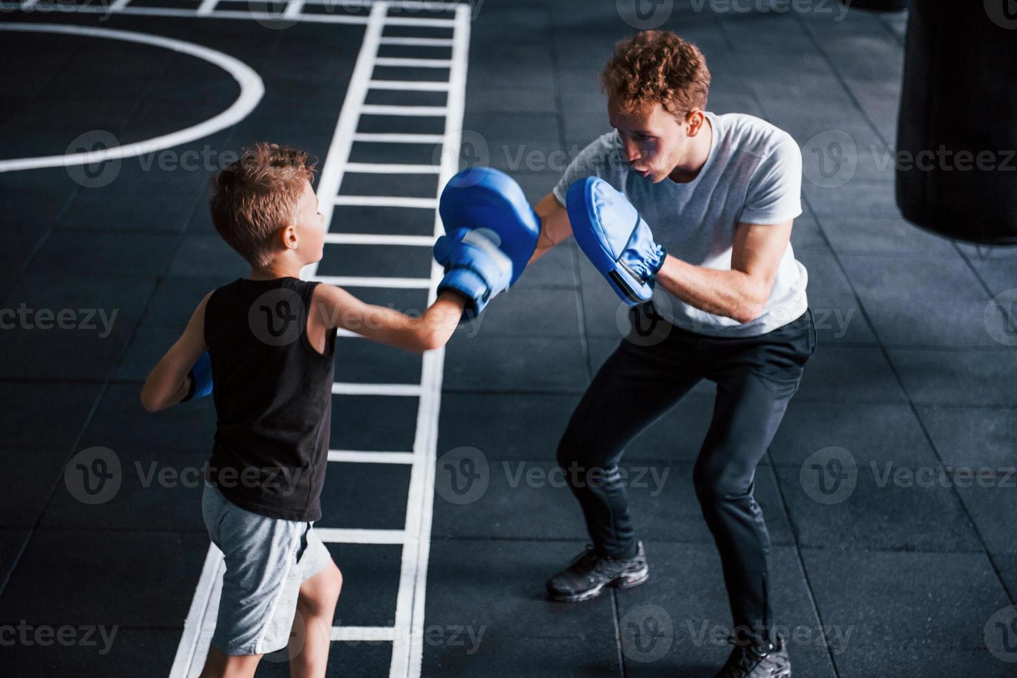 jeune entraîneur enseigne le sport de boxe aux enfants dans la salle de gym photo