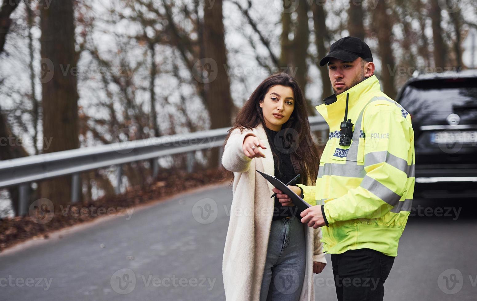 policier en uniforme vert parlant avec la femme propriétaire de la voiture sur la route photo