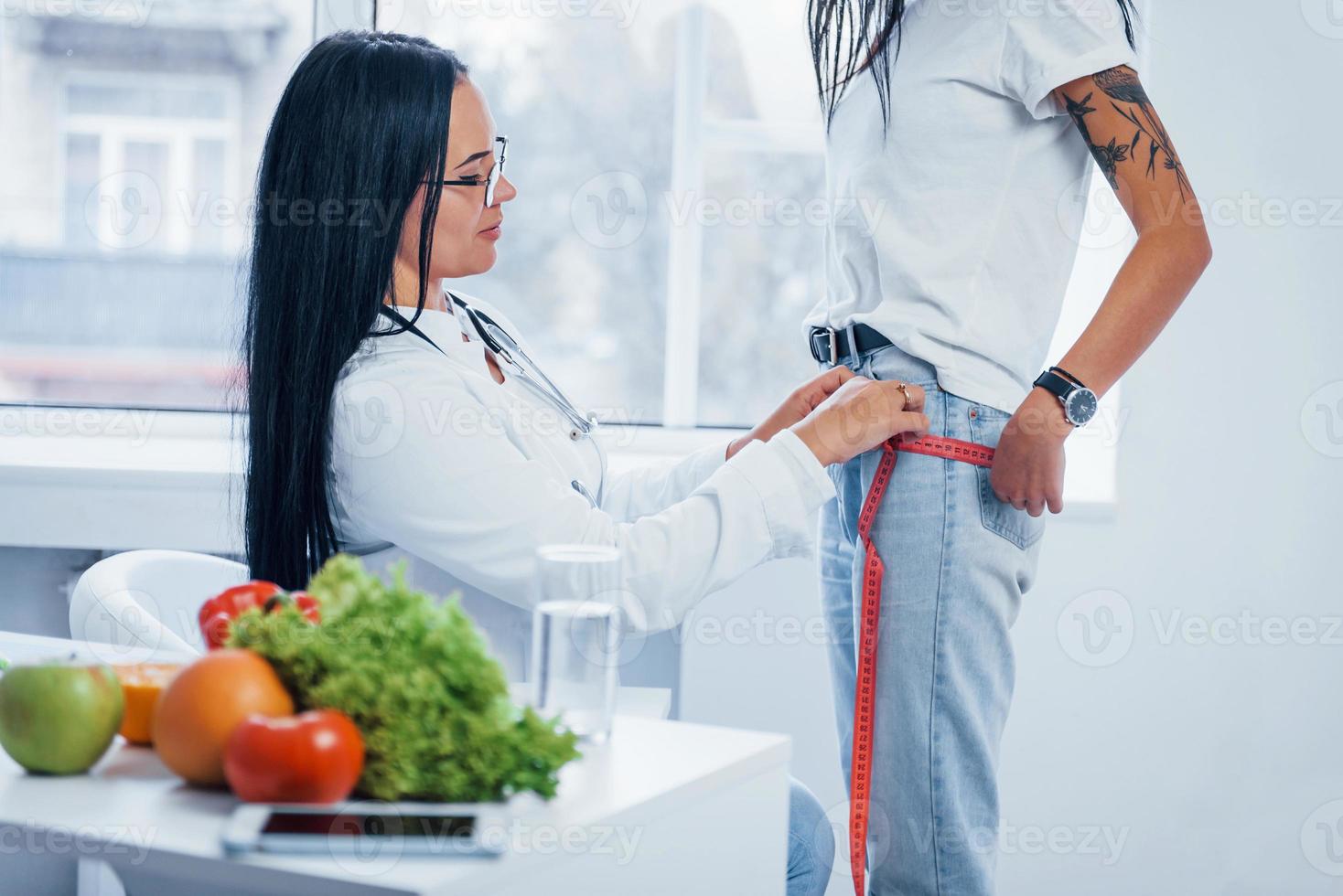 nutritionniste féminine mesurant la taille du patient par bande à l'intérieur du bureau photo