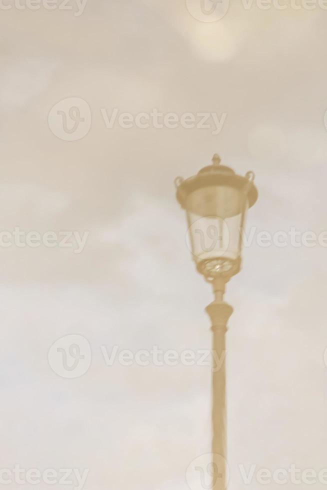 réverbère. reflet dans une flaque d'eau contre un ciel nuageux par temps nuageux. image floue photo