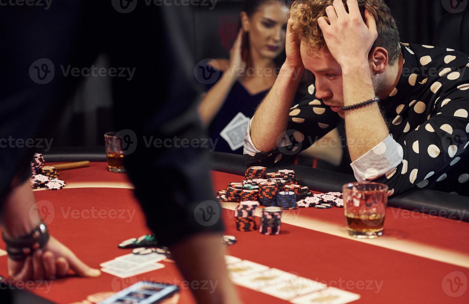 l'homme perd le jeu. groupe de jeunes élégants qui jouent au poker au casino ensemble photo