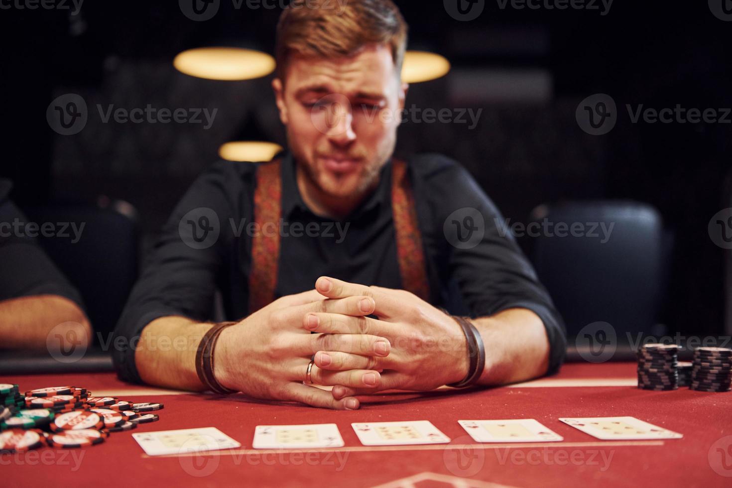 un jeune homme élégant est assis dans un casino et se sent mal parce qu'il perd une partie de poker photo