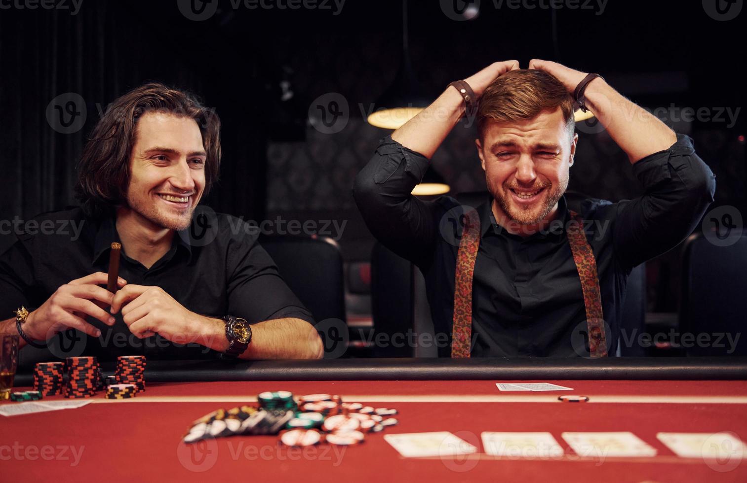 le gars perd son jeu. des jeunes élégants sont assis à table et jouent au poker au casino photo