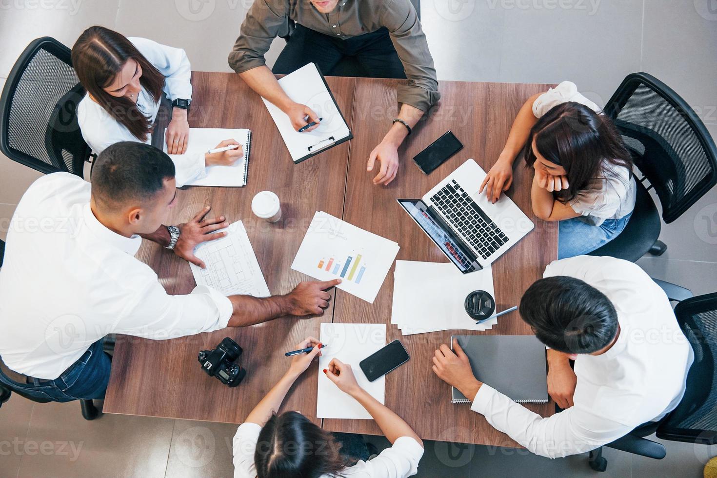 vue de dessus de jeunes gens d'affaires qui travaillent avec des documents et un ordinateur portable dans le bureau moderne photo