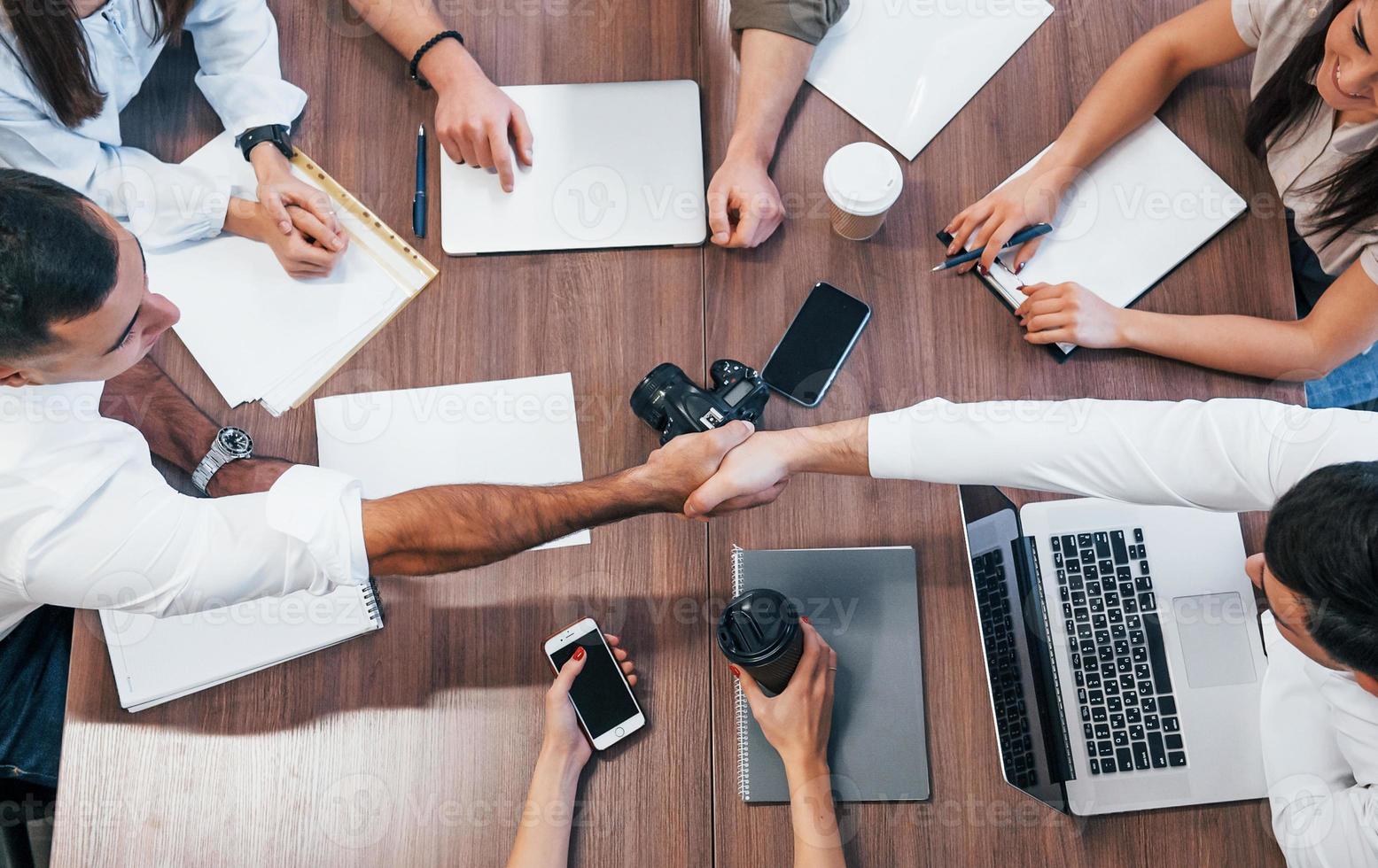 vue de dessus de jeunes gens d'affaires qui travaillent avec des documents et un ordinateur portable dans le bureau moderne photo