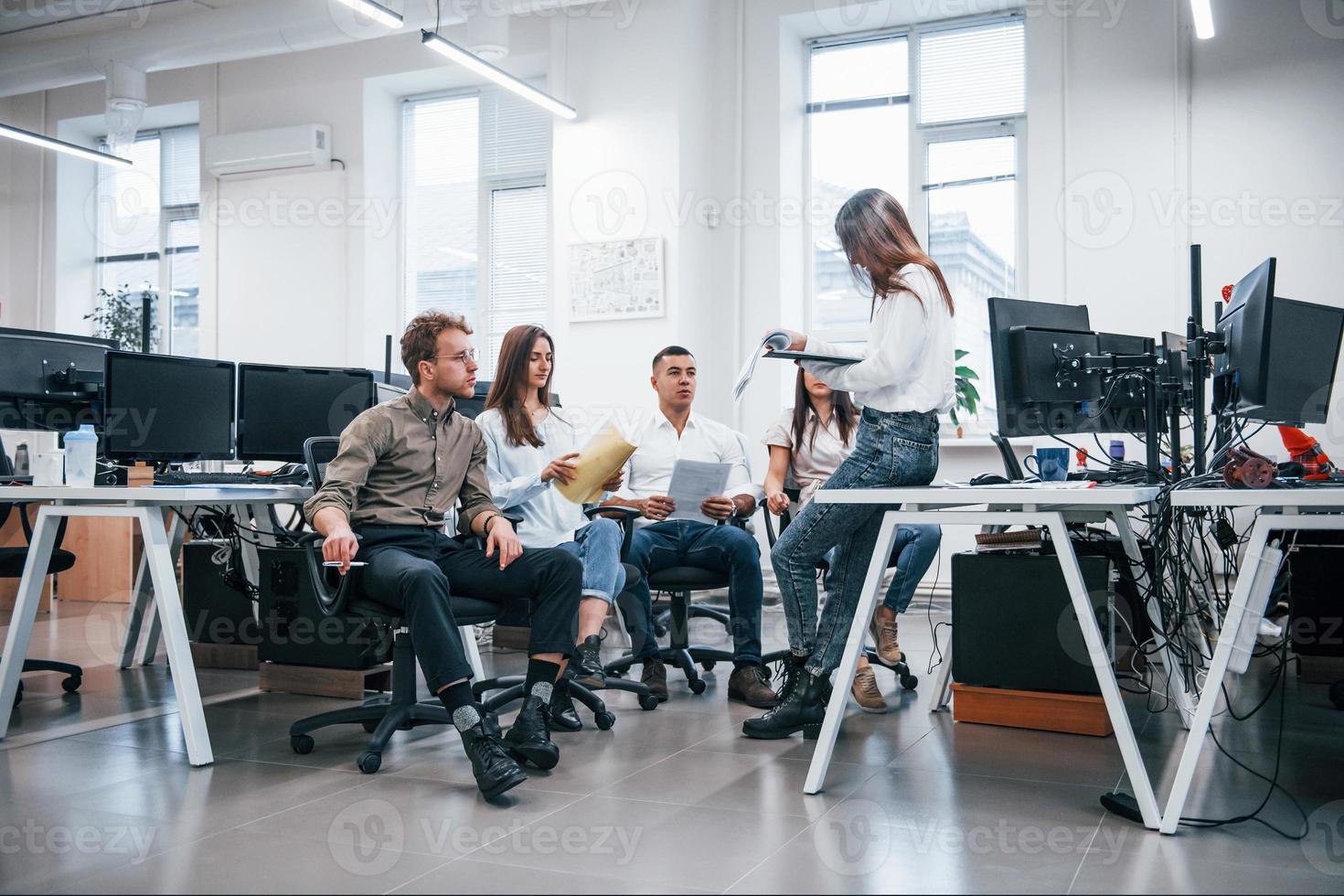 les gens parlent et travaillent ensemble dans le bureau moderne près des ordinateurs photo