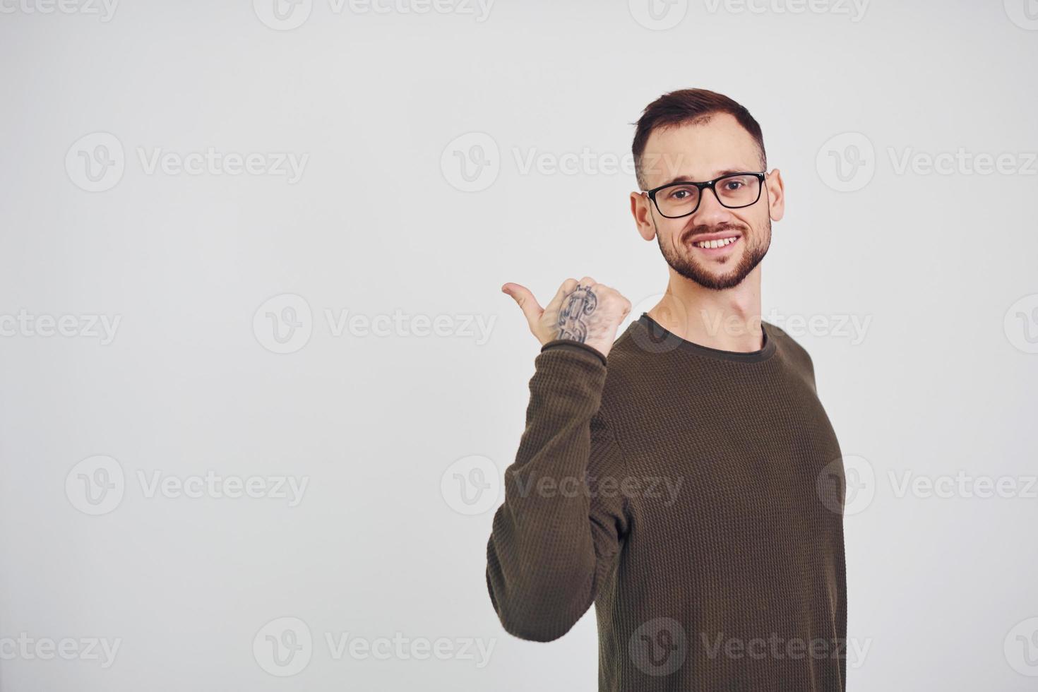 jeune homme à lunettes de soleil debout à l'intérieur sur fond blanc photo