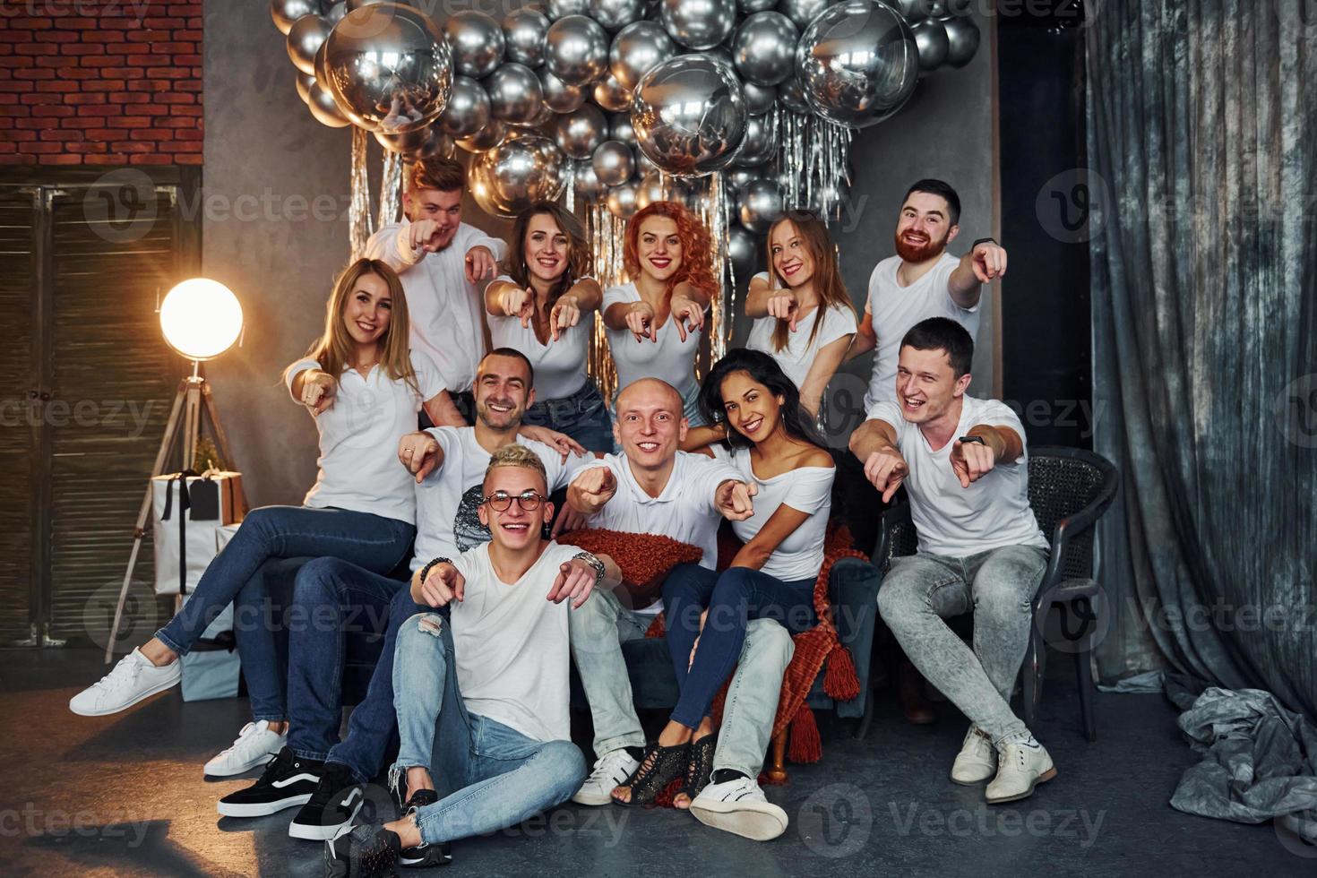 jeunes gens positifs assis et célébrant le nouvel an dans une salle décorée de noël avec des ballons ensemble photo