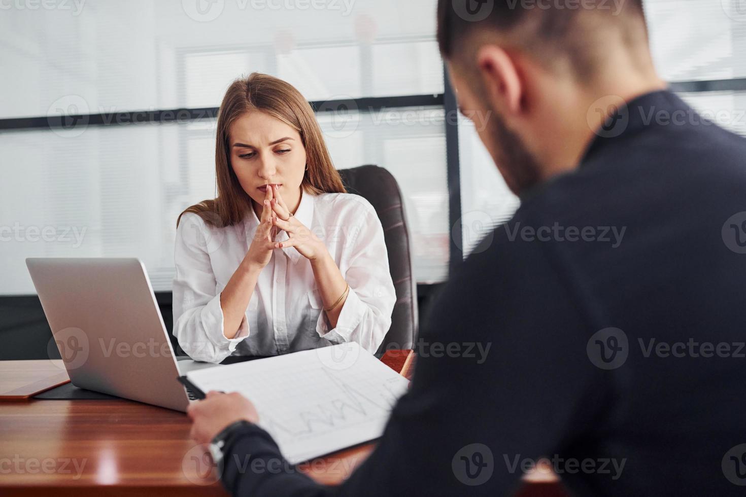 gars assis avec des documents. femme et homme en vêtements formels travaillant ensemble à l'intérieur au bureau par table photo