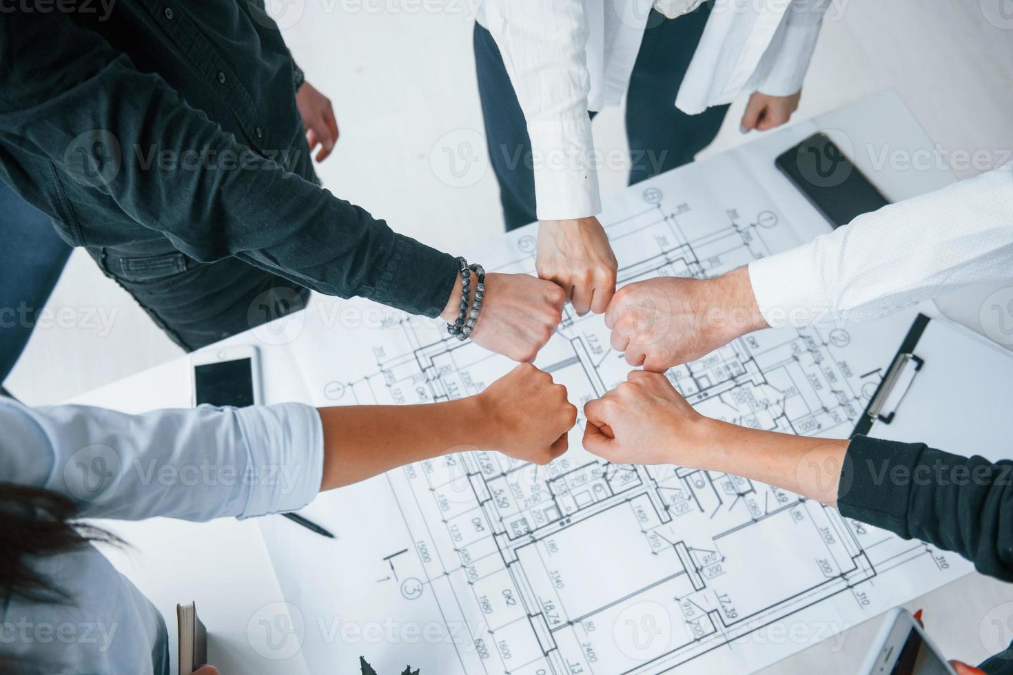 vue rapprochée des mains des gens d'affaires qui célèbrent le succès dans le bureau au-dessus du plan de construction qui est sur la table photo