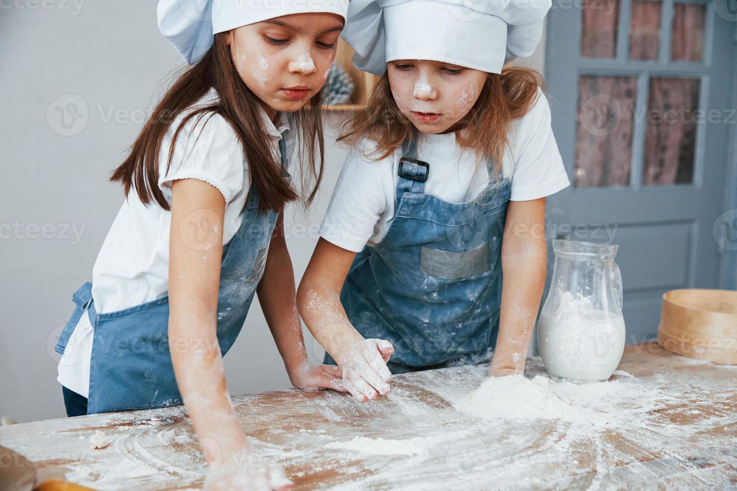 deux petites filles en uniforme de chef bleu préparant la nourriture dans la cuisine photo