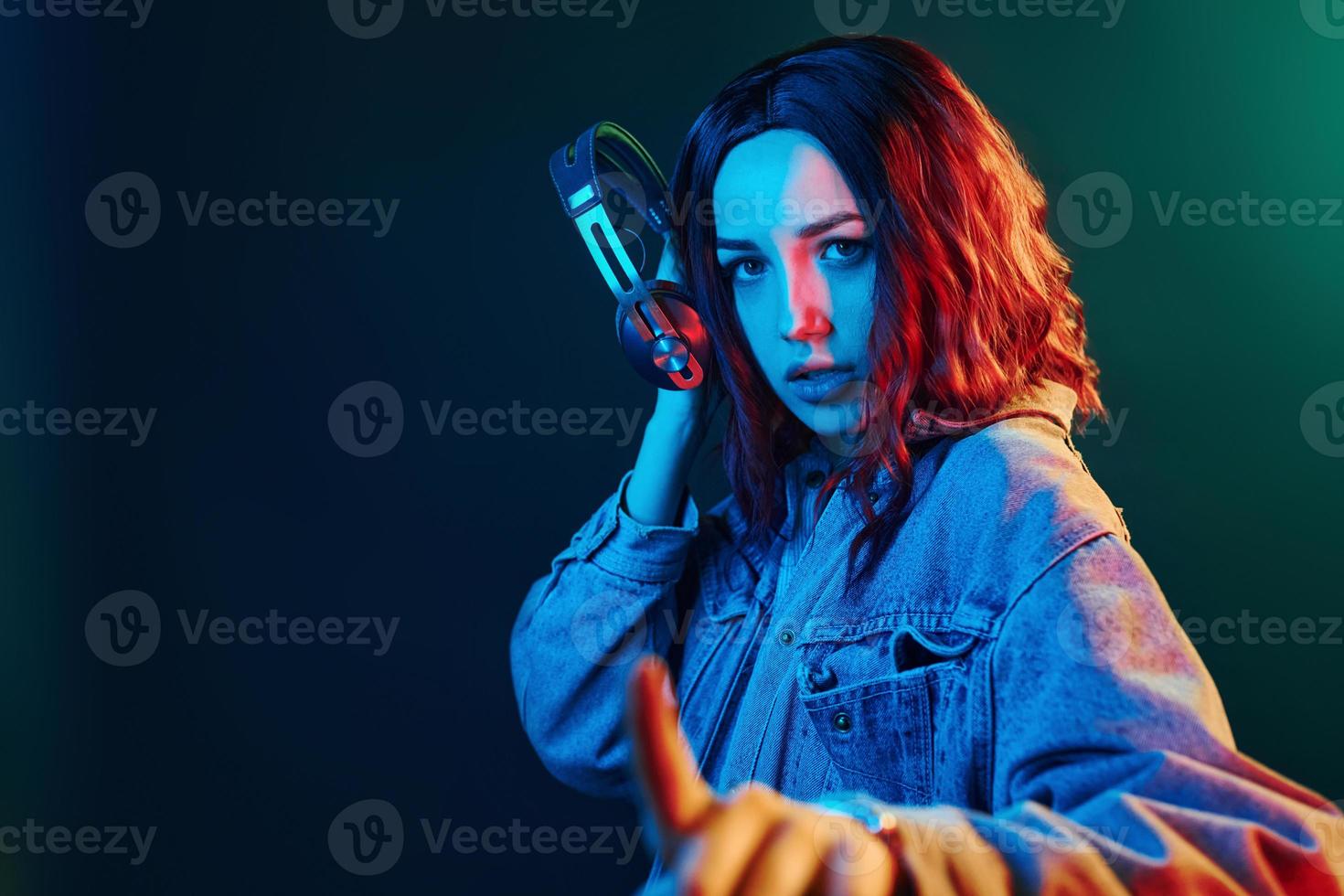 portrait de jeune fille qui écoute de la musique dans des écouteurs en néon rouge et bleu en studio photo