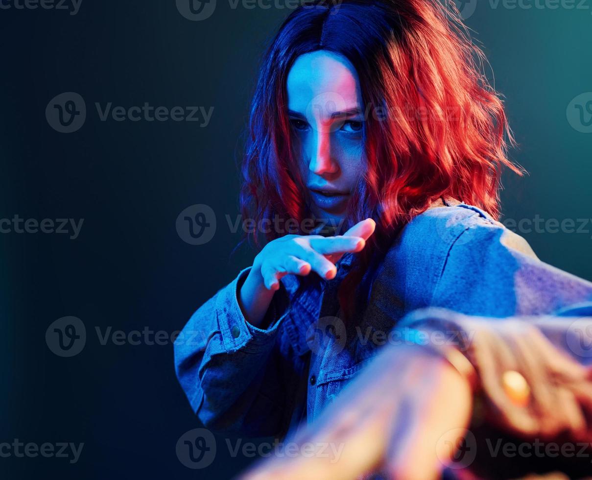 portrait de jeune fille aux cheveux bouclés qui danse en néon rouge et bleu en studio photo